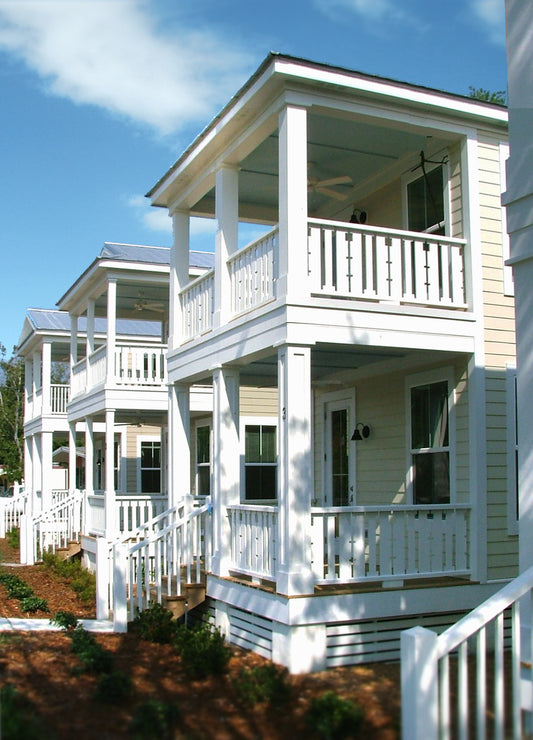 Photo of a row of three narrow, two-story houses with double height porches. Blue sky behind